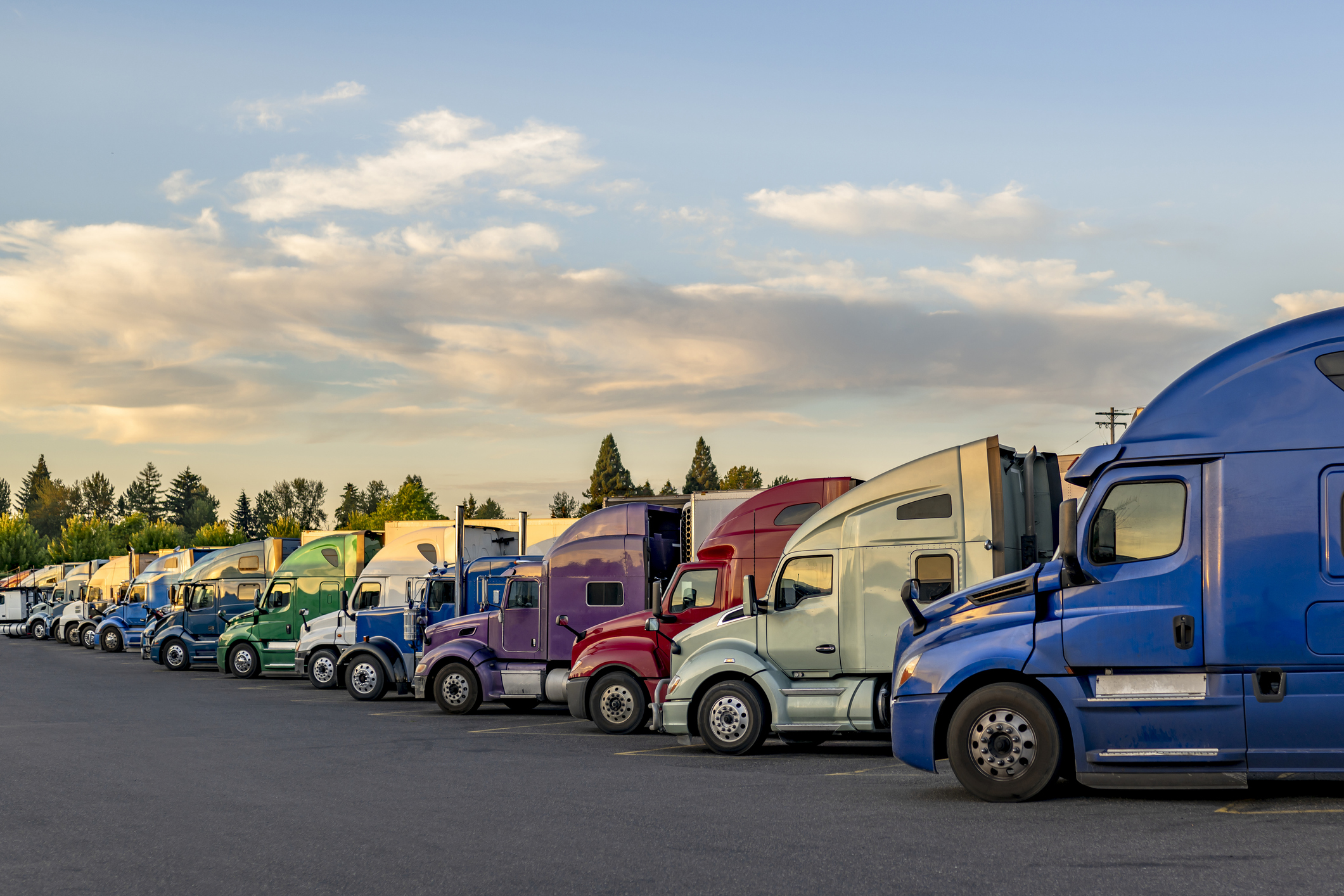 Professional carriers big rig semi trucks with semi trailers standing in row on truck stop parking lot taking a break stock photo - large.jpg